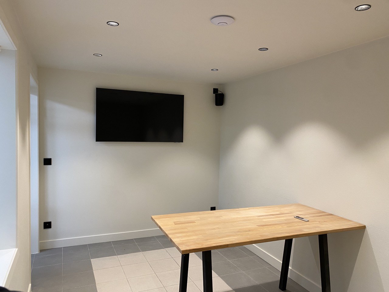 Eetruimte met wandgemonteerde TV en Sonos-speaker