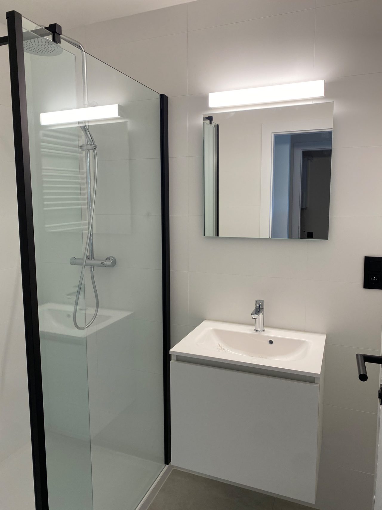 Badkamer met moderne spiegelverlichting en zwarte Niko afwerking